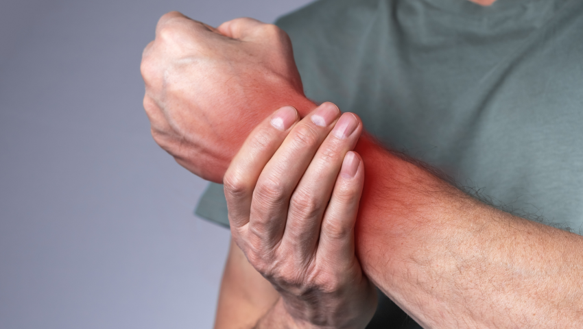 a partial image of a man clutching his reddened wrist that looks hurt or inflamed